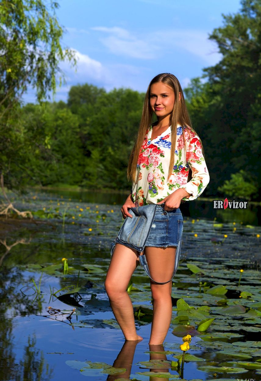 симпатичная девчонка в джинсовой юбке стоит ногами в оезер